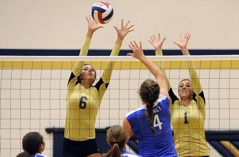 Helias' Molly Sandbothe (6) and Tory Wiley (1) try to block an attack by Quincy hitter Taylor Houghton during Monday night's match at Rackers Fieldhouse.