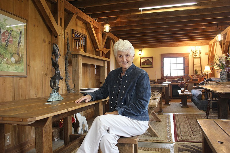 Carolyn Linton, creator of the Green Meadow Barn Company, sits at one of the the hand-crafted tables in her show room near Millersburg. Linton, who has been working with wood since childhood, said dining tables are one of her favorite pieces to build because she likes thinking about the family meals and memories that will be shared around them.