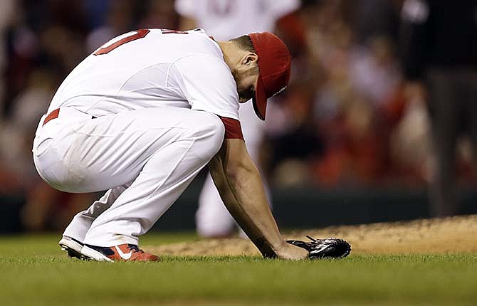 St. Louis Cardinals starting pitcher Shelby Miller bends down after throwing the ball away while trying to throw out Milwaukee Brewers' Matt Clark at second during the fifth inning of a baseball game Thursday, Sept. 18, 2014, in St. Louis. Miller was charged with a throwing error on the play.