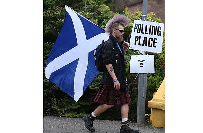 Chris McAleese holds a Saltire flag as he walks past Bannockburn Polling Station in Scotland on Thursday. People across Scotland rejected a referendum that proposed the region leave its 307-year-old union with England.