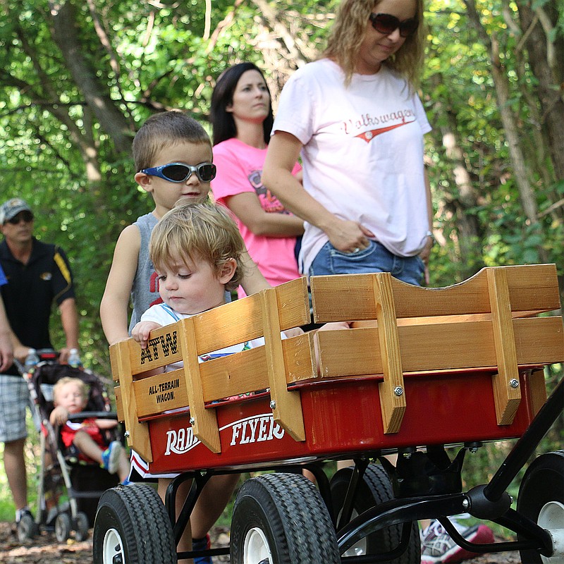Kyler Bohnert, 4, helps push a wagon carrying 20-month-old JT Wagoner at the Parents as Teachers roll and read event Saturday.