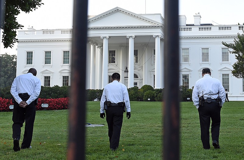 Uniformed Secret Service officers walk along the lawn on the North side of the White House on Saturday. The Secret Service is coming under renewed scrutiny after a man scaled the White House fence and made it all the way through the front door before he was apprehended.