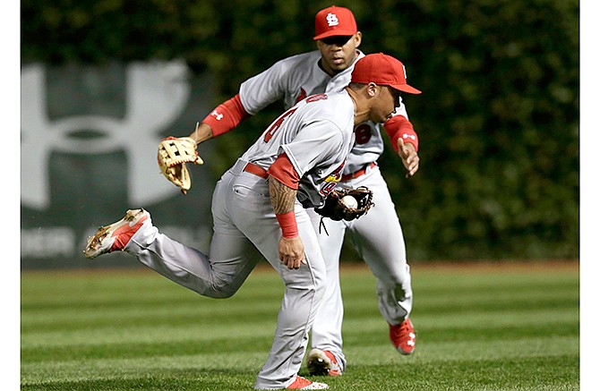 St. Louis Cardinals second baseman Kolten Wong, front, makes a catch of a fading fly ball by Chicago Cubs' Jorge Soler, in shallow right field, as right fielder Oscar Taveras comes over to assist during the third inning of a baseball game Wednesday, Sept. 24, 2014, in Chicago. 