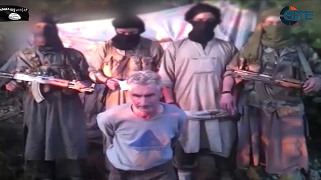 In this still image from video published on the Internet on Wednesday by a group calling itself Jund al-Khilafah, or Soldiers of the Caliphate, members of the group stand behind French mountaineer Herve Gourdel just before beheading him. In the video, the men pledge their allegiance to the leader of the Islamic State group, Abu Bakr al-Baghdadi, before killing Gourdel, 55, who they abducted on Sunday.