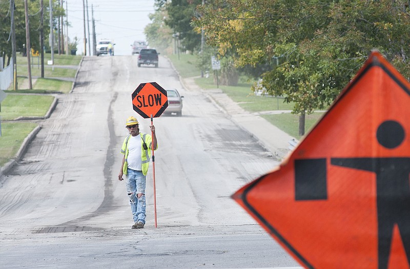 A worker with Columbia-based APAC of Missouri Inc. holds a sign to help direct traffic on 10th Street in Fulton on Thursday, Sept. 25, 2014, as crews prep the road.