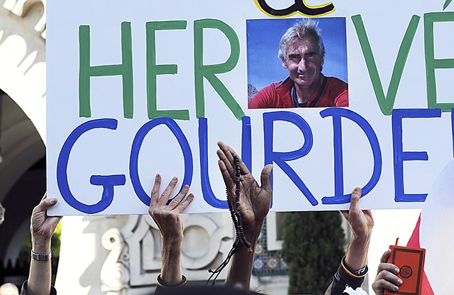 Muslims hold a sign paying homage to French mountaineer HervÃ© Gourdel, his photo in the center of the banner, who was beheaded by Islamist militants in Algeria, during a gathering in front of the Paris Grand Mosque, Friday.