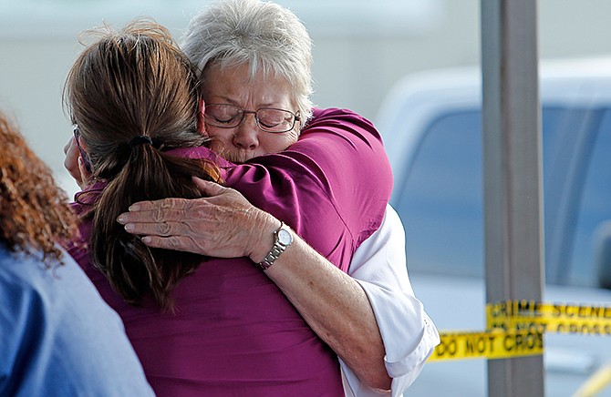 Employees and friends wait behind a tape for word of loved ones as police investigate an incident at Vaughn Foods on Thursday, Sept. 25, 2014 in Moore, Okla. Police Friday a man who had been fired from the food processing plant beheaded a woman with a knife and was attacking another worker when he was shot and wounded by a company official. (AP Photo/The Oklahoman, Steve Sisney)