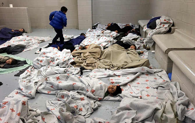 In this June 18, 2014, file photo, detainees sleep in a holding cell at a U.S. Customs and Border Protection processing facility in Brownsville,Texas. More than half of the nearly 60,000 Central America children who have arrived on the U.S.-Mexico border in the past year still don't have lawyers to represent them in immigration court and many of those who do have volunteer attorneys scrambling to brush up on immigration law. Advocates are holding training sessions to help private sector attorneys learn how to work with traumatized, Spanish-speaking children, many of whom have come fleeing violence. 