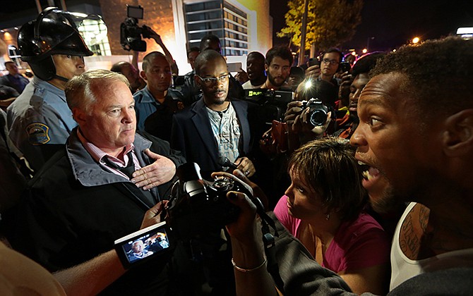 Ferguson Police Chief Tom Jackson, left, speaks before protesters in front of the Ferguson Police Department, on Thursday, Sept. 25, 2014.