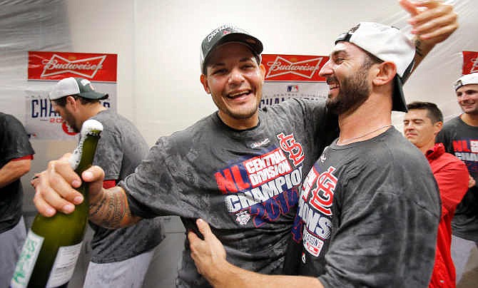 St. Louis Cardinals' Yadier Molina, left, and Daniel Descalso celebrate after the Cardinals' baseball game against the Arizona Diamondbacks, Sunday, Sept. 28, 2014, in Phoenix. The Cardinals clinched their second straight NL Central title before the first pitch and closed out the regular season with a 1-0 win over the Diamondbacks. The Cardinals were already in the postseason entering the day and celebrated the division title in the dugout minutes before first pitch, when Cincinnati's 4-1 win over Pittsburgh was announced.