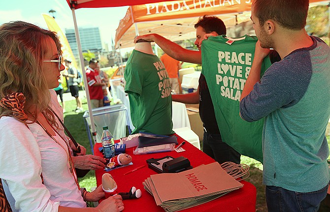 Homage employees sell shirts reading "Peace Love & Potato Salad" at PotatoStock, Zack "Danger" Brown's Kickstarter-funded event, at the Columbus Commons in Columbus, Ohio on Saturday, Sept. 27, 2014. (AP Photo/The Columbus Dispatch, Jenna Watson)