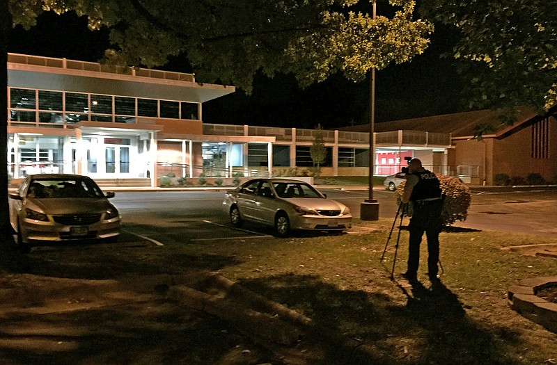 A police officer takes pictures outside the Ferguson Community Center on Saturday after authorities say a police officer was shot.