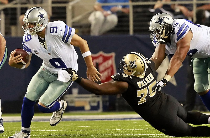 Dallas Cowboys quarterback Tony Romo (9) escapes from New Orleans Saints defensive end Tyrunn Walker (75) during the second half of an NFL football game Sunday.