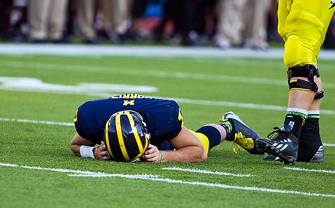 In this Sept. 27, 2014, photo, Michigan quarterback Shane Morris lays on the field after taking a hit in the fourth quarter of an NCAA college football game against Michigan in Ann Arbor, Mich. Early Tuesday, Sept. 30, 2014, roughly 12 hours after embattled Michigan coach Brady Hoke said he'd been given no indication that Morris had been diagnosed with a concussion, athletic director Dave Brandon revealed in a post-midnight statement that the sophomore did appear to have sustained one.