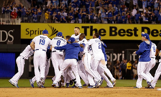 Kansas City Royals mob teammate Salvador Perez after he hit a walk-off single in the 12th inning to defeat the Oakland Athletics 9-8 in the AL wild-card playoff baseball game Tuesday, Sept. 30, 2014, in Kansas City, Mo. 