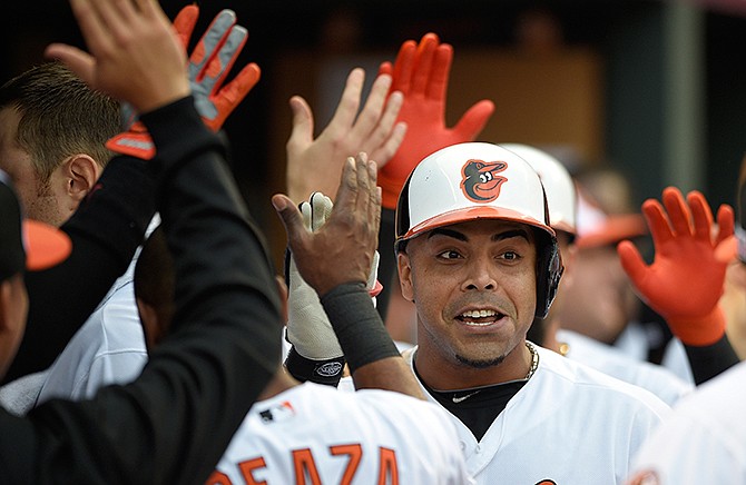 Baltimore Orioles designated hitter Nelson Cruz is greeted in the dugout after hitting a two-run home run in the first inning against the Detroit Tigers during Game 1 of baseball's AL Division Series, Thursday, Oct. 2, 2014, in Baltimore.