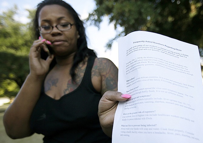 Candis Holt, a mother of a kindergarten student at L.L. Hotchkiss Elementary school, shows a piece of paper handed to her by the school with frequently asked questions about the Ebola virus after she dropped her child off, Thursday, in Dallas. Hotchkiss has been identified by the Dallas Independent School District as one of the schools where one or more of the students attend that came in contact with the man diagnosed with having the Ebola virus. 