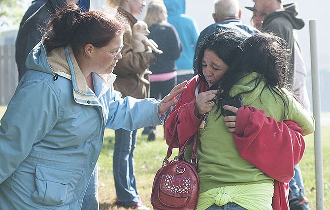 Theresa Hodge of Holts Summit hugs her daughter, Chyann Hodge, 12, Friday outside their home at the Evergreen Apartment Complex. A fire ignited one building around 1 p.m. Hodge and her children live in the neighboring building, and the mother feared the fire would spread to their home.