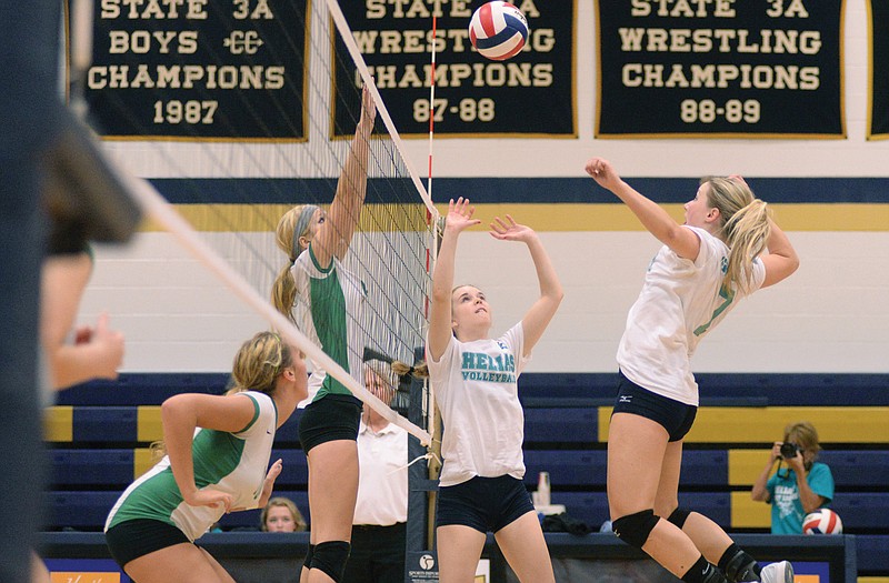 Lindsey Griggs (right) spikes a ball set by Ashley Dudenhoeffer of Helias against defendersAllison Maxwell (left) and Alexa Stegemann during Thursday's match at Rackers Fieldhouse. 