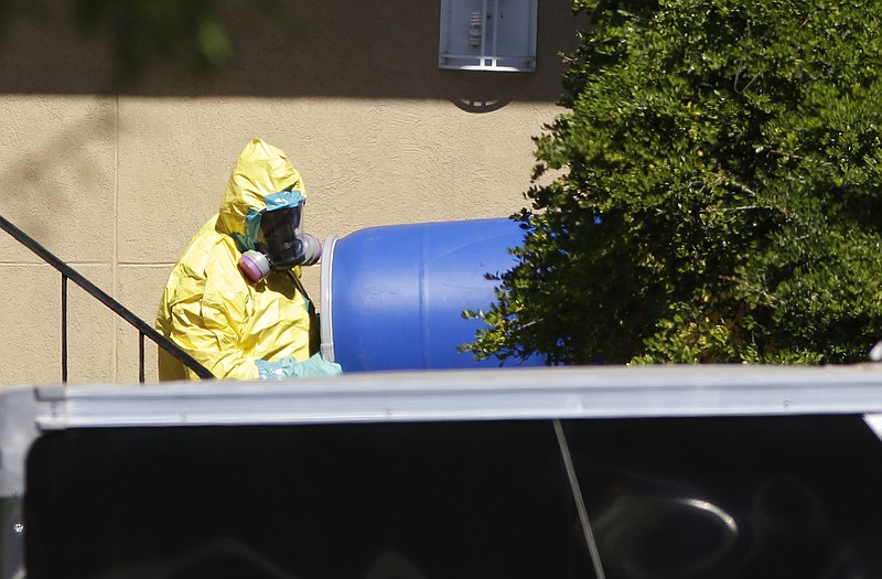 A hazardous material cleaner removes a blue barrel from the apartment in Dallas, where Thomas Eric Duncan, the Ebola patient who traveled from Liberia to Dallas stayed last week. The family living there has been confined under armed guard while being monitored by health officials.
