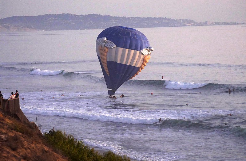 A hot air balloon dips into the ocean in Cardiff-by-the-Sea, a beach community in Encinitas, Calif. A man was proposing to his girlfriend during their sunset ride Sunday when the balloon drifted off course and hovered over the water, prompting a rescue by lifeguards and surfers.
