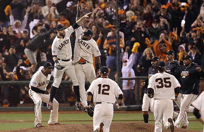 San Francisco Giants first baseman Brandon Belt, upper left, high fives third baseman Pablo Sandoval and teammates after the Giants beat Washington Nationals in Game 4 of baseball's NL Division Series in San Francisco, Tuesday, Oct. 7, 2014. The Giants won 3-2 to win the series.