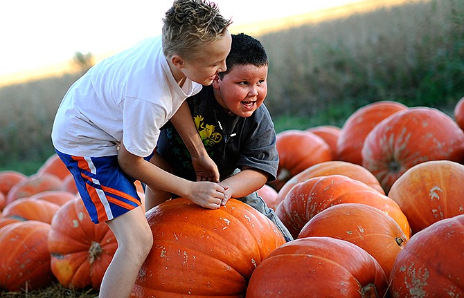 In this News Tribune file photo, Pals Tucker Gleason, left, and Quinton Willis wrestle over who gets the prime seat atop one of the large pumpkins during the 2013 Hartsburg Pumpkin Festival.