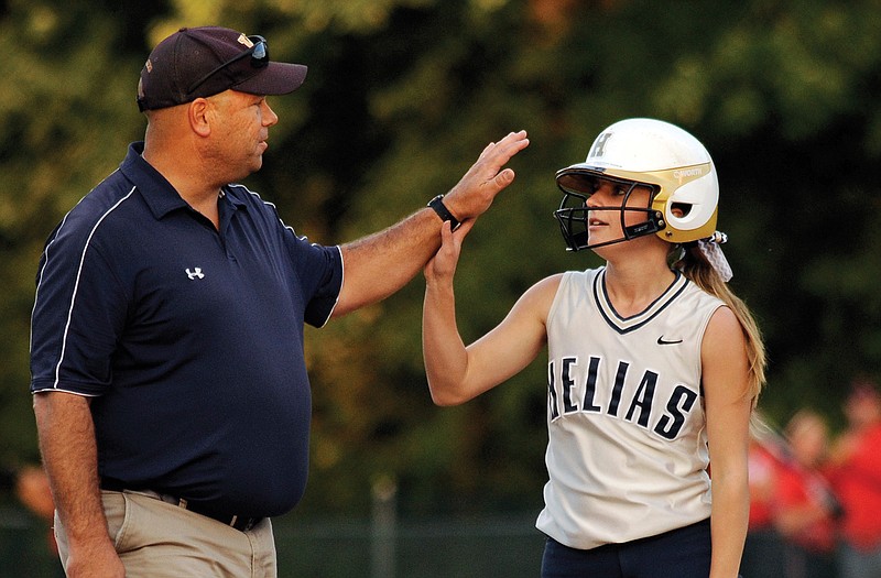 Helias' Riley Bond high fives coach Dan Campbell after hitting reaching third during Wednesday's district game against School of the Osage. 