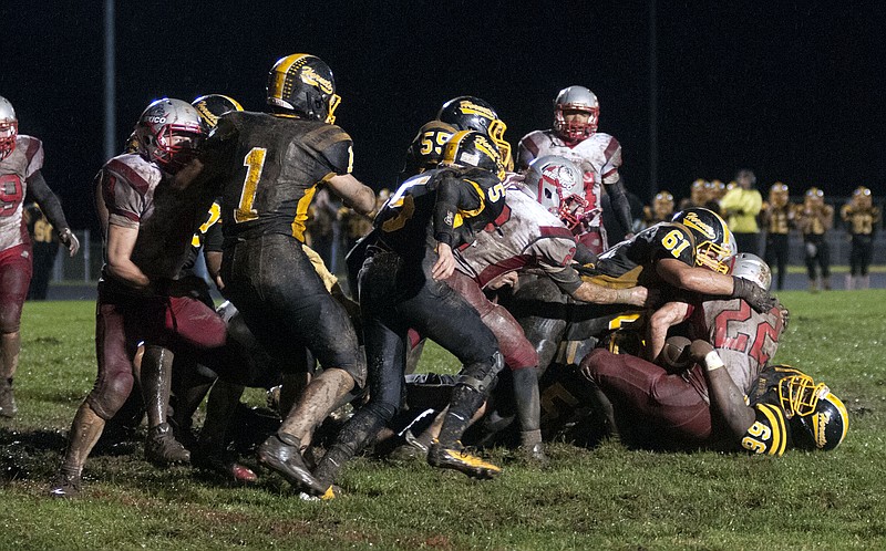 Fulton junior defensive linemen Alex Garner (61) and Elisha Eniade smother Mexico junior running back Karsten Eckern during the Hornets' 2013 NCMC loss to the Bulldogs in the annual Highway 54 Bowl on Friday night at Robert E. Fisher Stadium.