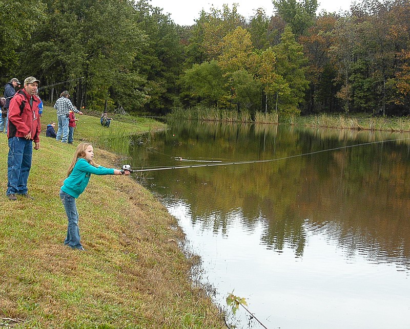 Miranda Stuart learns to cast at the Shooters Club lake as Conservation Department fisheries specialist Scott Williams looks on.