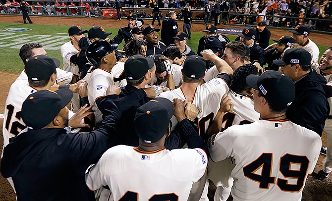 San Francisco Giants' Travis Ishikawa is swarmed by teammates after hitting a walk-off three-run home run during the ninth inning of Game 5 of the National League baseball championship series against the St. Louis Cardinals Thursday, Oct. 16, 2014, in San Francisco. The Giants won 6-3 to advance to the World Series.