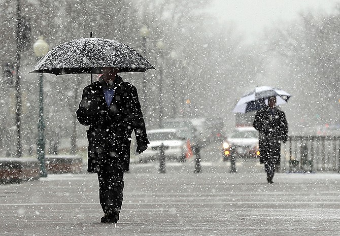 In this December 2013 file photo, snow falls as people begin to arrive to the Capitol Building in Washington. Federal forecasters don't expect this winter to be a chilly sequel to last year's dreaded polar vortex and California's rain-blocking weather system.