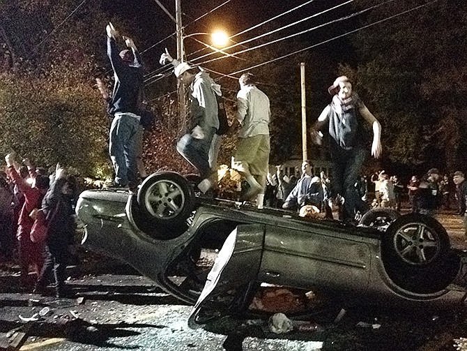 People stand atop an overturned car in Keene, New Hampshire on Saturday during a night of violent parties that led to destruction, dozens of arrests and multiple injuries, near the city's annual pumpkin festival.  