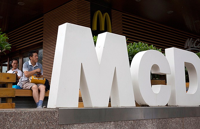 In this July 22, 2014 file photo, a man rests outside a McDonald's restaurant in Beijing. McDonald's reports quarterly financial results on Tuesday, Oct. 21, 2014.