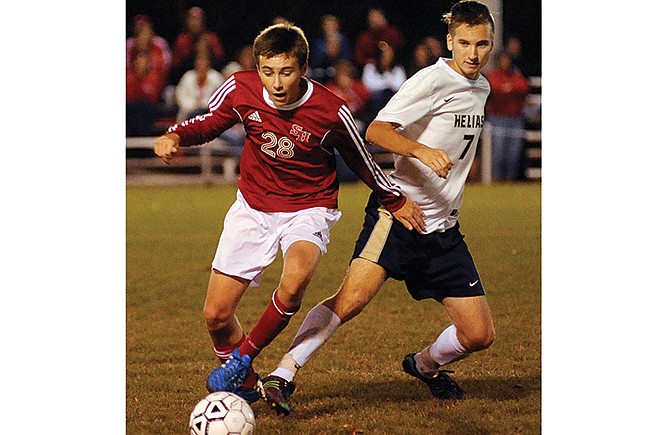 Helias forward Ian Luebbert fouls Sacred Heart's Teagan Trammell as he tries to make a tackle at midfield in the first half of Wednesday's match at 179 Soccer Park in Jefferson City.