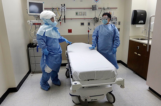 In this Oct. 8, 2014, file photo, Bellevue Hospital nurse Belkys Fortune, left, and Teressa Celia, Associate Director of Infection Prevention and Control, pose in protective suits in an isolation room, in the Emergency Room of the hospital, during a demonstration of procedures for possible Ebola patients in New York.