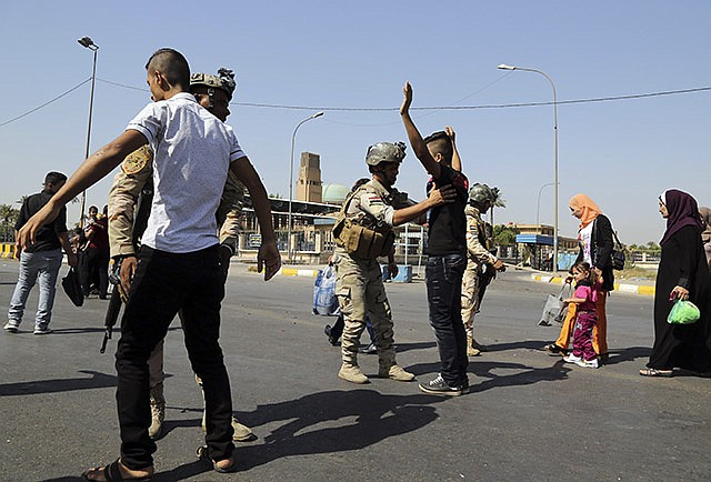 In this Oct. 6 photo, Army soldiers search Iraqis amid tight security during Eid al-Adha celebrations in Baghdad, Iraq. Iraq's fractured army has begun to regroup and stage modest, localized attacks on the Islamic State militants who routed them last spring and summer, but they are unlikely to be ready to launch a major counteroffensive for many months, senior U.S. military officials said Thursday.