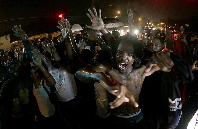 In this Aug. 17 photo, people defy a curfew before smoke and tear gas was fired to disperse a crowd protesting the shooting of teenager Michael Brown in Ferguson. Missouri police, in advance of a grand jury decision on whether to charge a white police officer who fatally shot a black 18-year-old, are making extensive preparations hoping to avoid a repeat of violent clashes between protesters and police. 