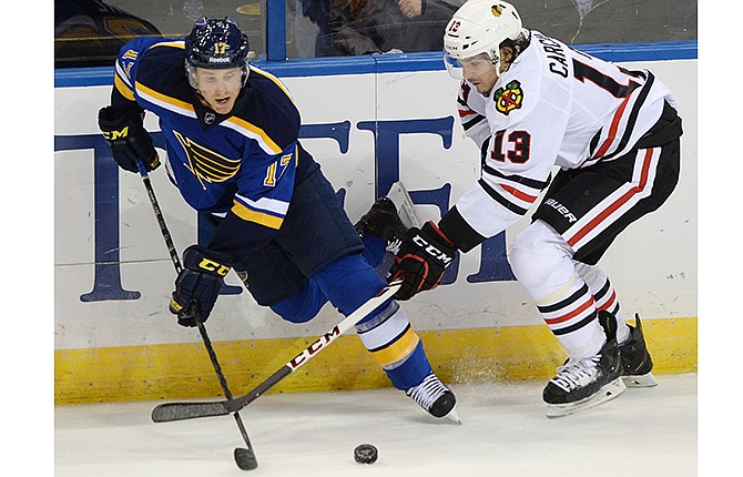 St. Louis Blues' Jaden Schwartz (17) and Chicago Blackhawks' Daniel Carcillo (13) reach for the puck during the third period of an NHL hockey game, Saturday, Oct. 25, 2014, in St. Louis. The Blues won 3-2.