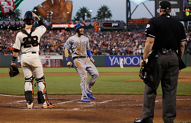 Home plate umpire Hunter Wendelstedt and San Francisco Giants catcher Buster Posey watch as Kansas City Royals Eric Hosmer scores on an RBI single by Salvador Perez during the third inning of Game 4 of baseball's World Series Saturday, Oct. 25, 2014, in San Francisco. Lorenzo Cain also scored on the hit. 