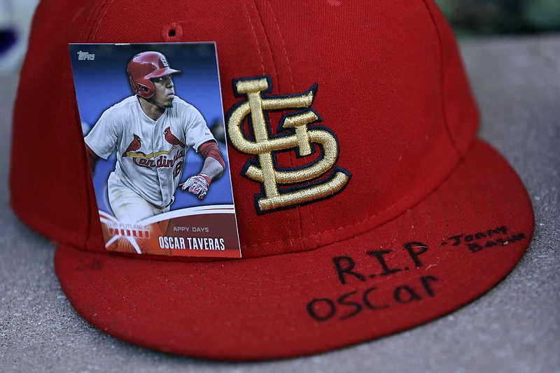 A baseball card showing Oscar Taveras is attached to a hat as part of a makeshift memorial Monday outside Busch Stadium.