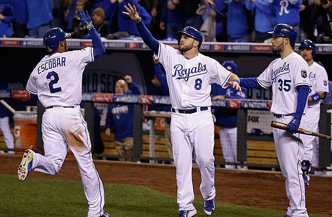 Kansas City Royals Alcides Escobar (2) is congratulated by teammates Mike Moustakas (8) and Rusty Kuntz (15) after scoring on an two-run RBI single by Lorenzo Cain during the second inning of Game 6 of baseball's World Series against the San Francisco Giants Tuesday, Oct. 28, 2014, in Kansas City, Mo.