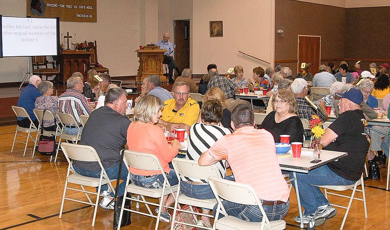 Contestants in the Library "Smartypants Trivia Challenge" ponder the answer to a question. Phil Lewis, seen in the background, serves as master of ceremonies for the event.