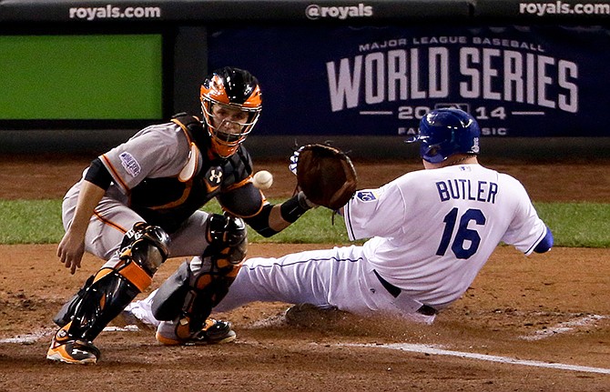 Kansas City Royals' Billy Butler scores past San Francisco Giants catcher Buster Posey on a hit by Alex Gordon during the second inning of Game 7 of baseball's World Series Wednesday, Oct. 29, 2014, in Kansas City, Mo. 