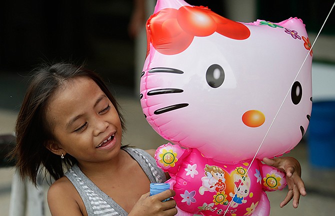 In this Friday, Oct. 17, 2014 photo, a girl admires a Hello Kitty balloon sold in Manila, Philippines. When she came to life in 1974, she was a kitty without a name, sitting sideways in blue overalls and a big red bow, on a coin purse for Japanese girls. On Saturday, Nov. 1, fans around the world celebrate the 40th anniversary of this global icon of "cute-cool." That is, Hello Kitty. Hello Kitty is featured on about 50,000 items in some 130 countries.