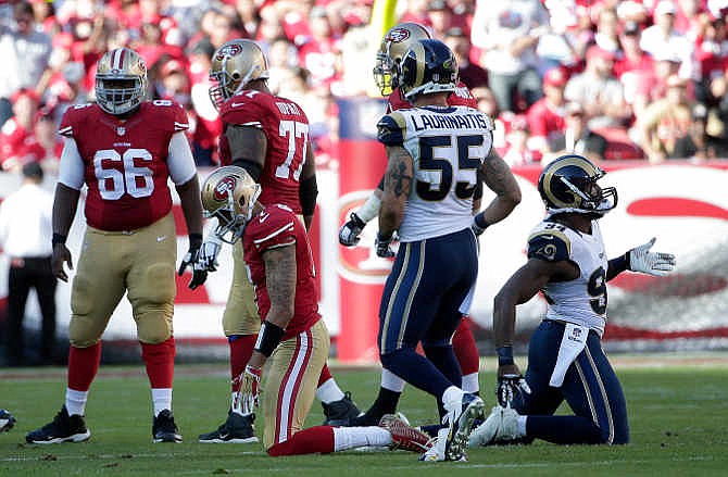 San Francisco 49ers quarterback Colin Kaepernick, bottom left, kneels after losing a fumble against the St. Louis Rams during the second quarter of an NFL football game in Santa Clara, Calif., Sunday, Nov. 2, 2014.