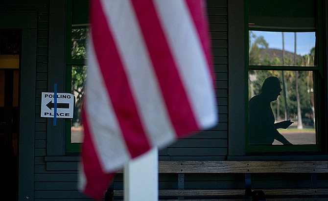 A voter is reflected in the window as he leaves after casting his ballot at Hollywood Heritage Museum Tuesday, Nov. 4, 2014, in Los Angeles. 