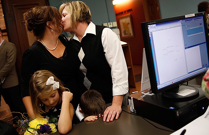 Kelley Harris, top left, and Kelly Barnard kiss as they apply for a marriage license accompanied by their two children, Mackenzie Harris, bottom left, and Cooper Harris, bottom right, Wednesday, Nov. 5, 2014, at City Hall in St. Louis. St. Louis Circuit Judge Rex Burlison overturned Missouri's ban on gay marriage on Wednesday saying the law is unconstitutional.