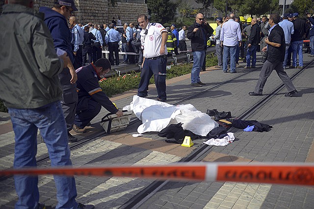 The body of a Palestinian driver who rammed his vehicle into a crowded train platform lies at the scene in Jerusalem on Wednesday. Police said the motorist slammed his car into the train platform in east Jerusalem killing one person and injuring 13 .He then backed out and proceeded to drive away, hitting several cars along the way, then got out of the car and attacked a group of civilians and police officers on the side of the road with a metal bar before he was shot and killed.