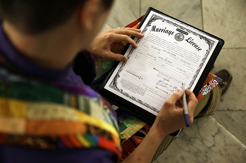 Rev. Katie Hotze-Wilton signs a Missouri marriage license after performing a marriage ceremony for April Dawn Breeden and her long-time partner Crystal Pearis Wednesday at City Hall in St. Louis. St. Louis Circuit Judge Rex Burlison overturned Missouri's ban on gay marriage on Wednesday saying the law is unconstitutional. (AP Photo/Jeff Roberson)